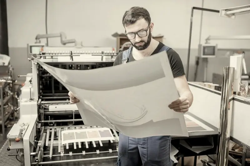 Impresor revisando un pliego recién salido de la máquina