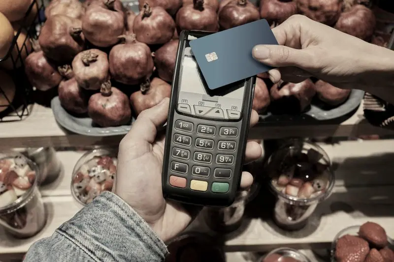 Cliente pagando con tarjeta en un datáfono junto a la fruta