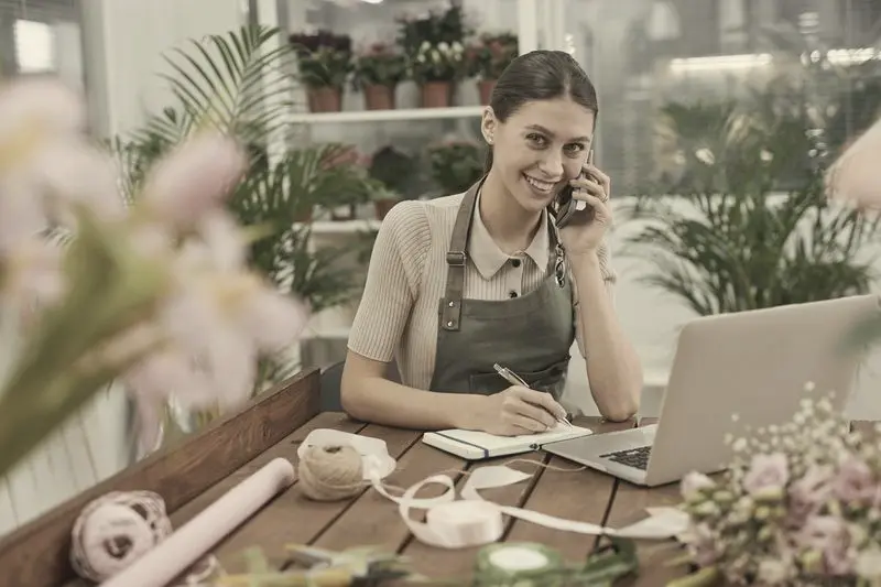 Dueña de una floristería trabajando con el portátil en su tienda