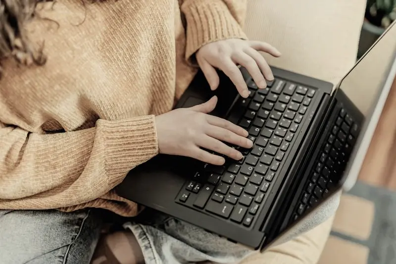 Manos escribiendo en el teclado de un portátil