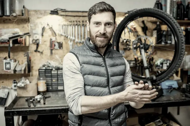 Mecánico en su taller de bicicletas, con las herramientas en la pared