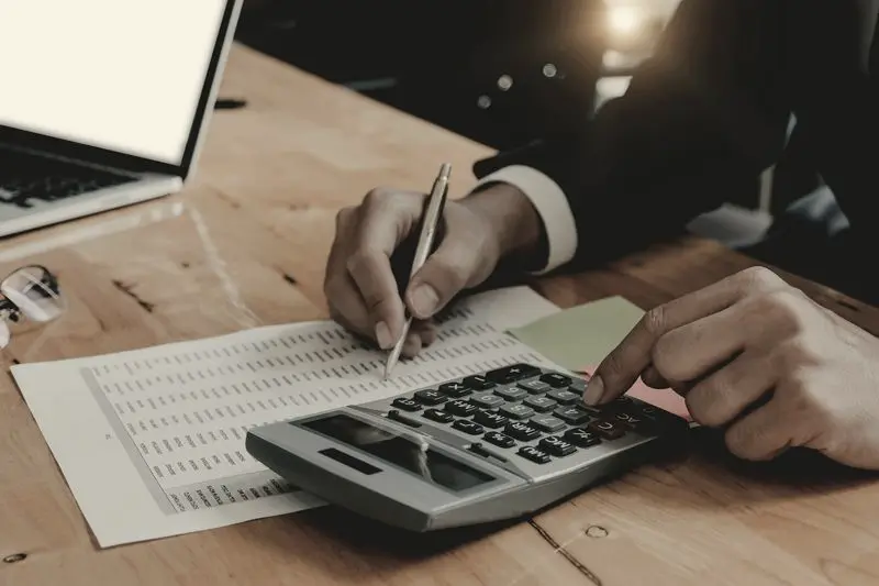 Persona haciendo cuentas con una calculadora sobre la mesa