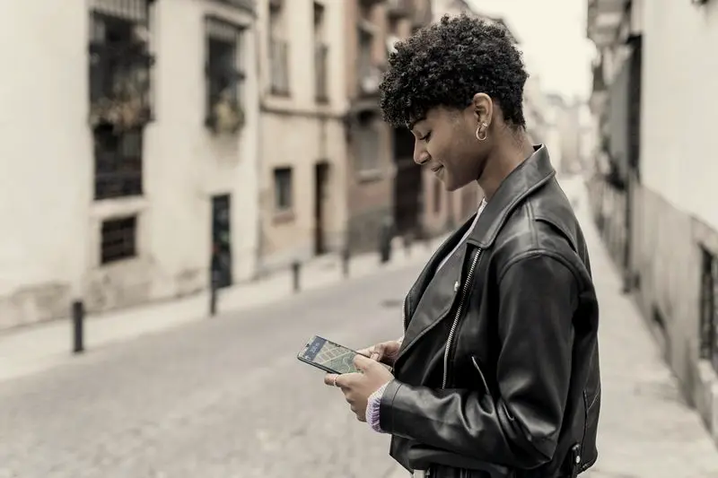 Chica consultando un mapa en el móvil en una calle con comercios