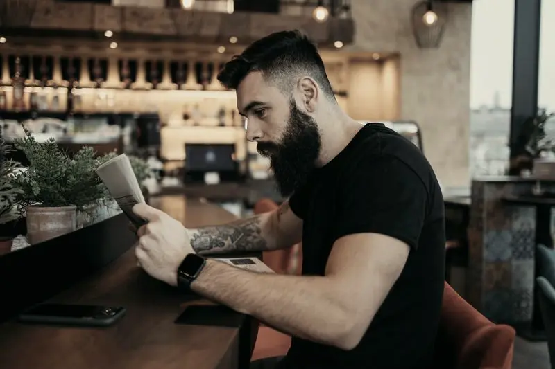 Hombre leyendo en el móvil en la barra de una cafetería