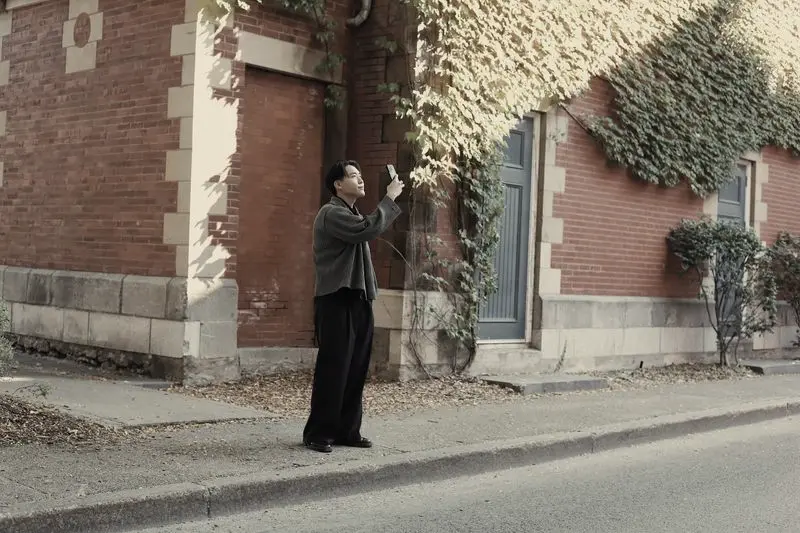 Hombre buscando algo en una calle, junto a una fachada