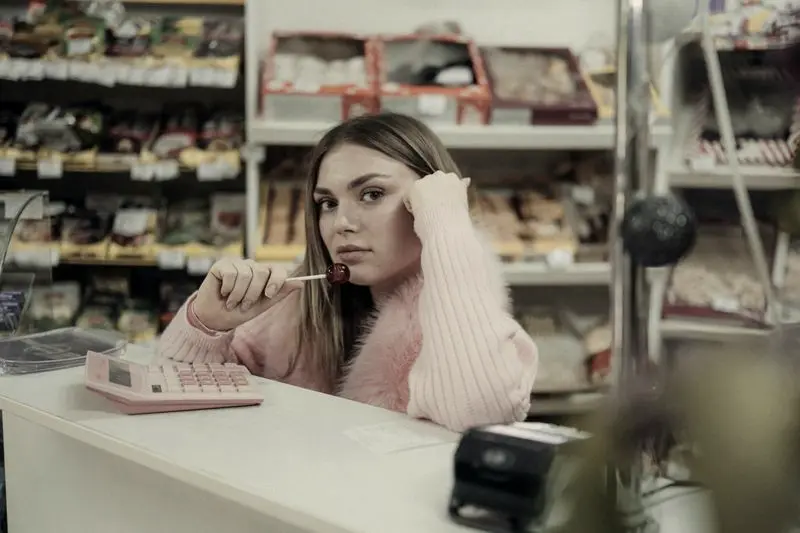 Dependienta aburrida en la caja de una tienda vacía