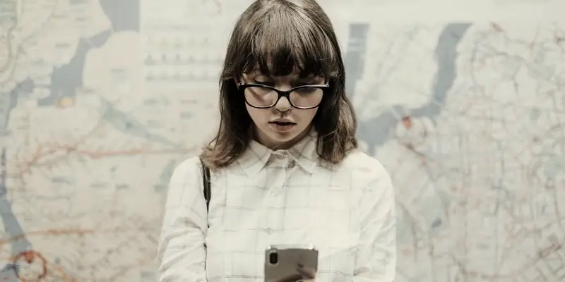 Mujer buscando un sitio en el móvil delante de un mapa