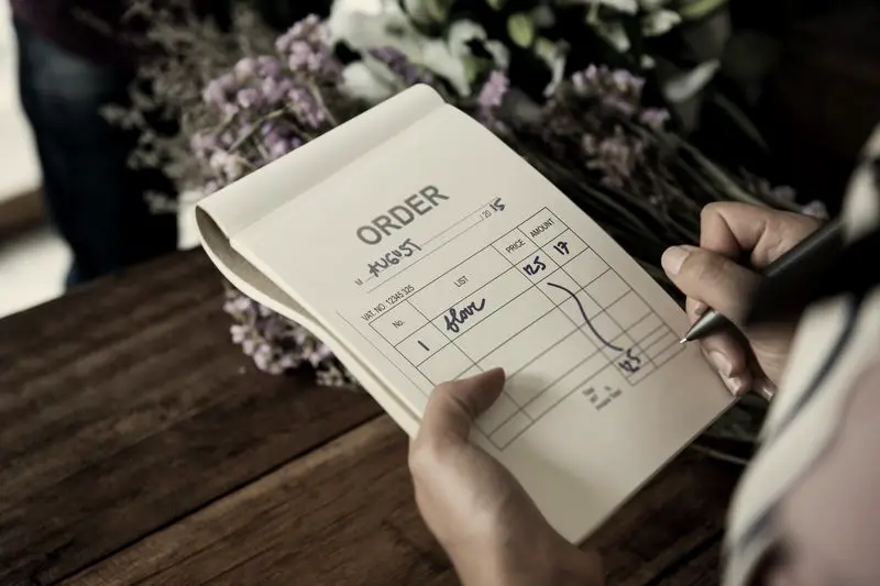 Libreta de pedidos entre flores en una floristería